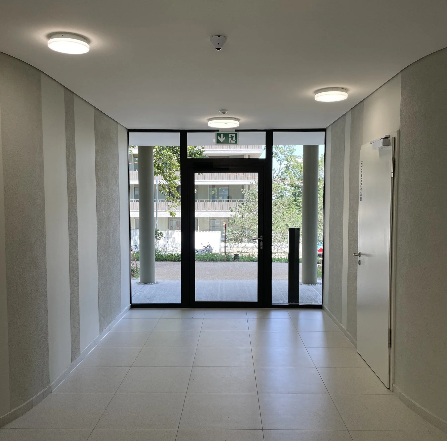 Hall d'entrée d'un immeuble résidentiel à Genève avec faux-plafond et finitions décoratives murales réalisés par DSD SA