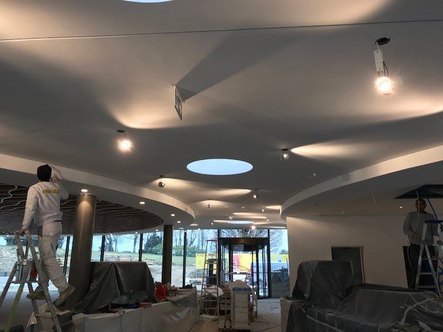 Faux-plafond décoratif à formes courbes et puits de lumière circulaires en cours de finition par DSD SA à Genève