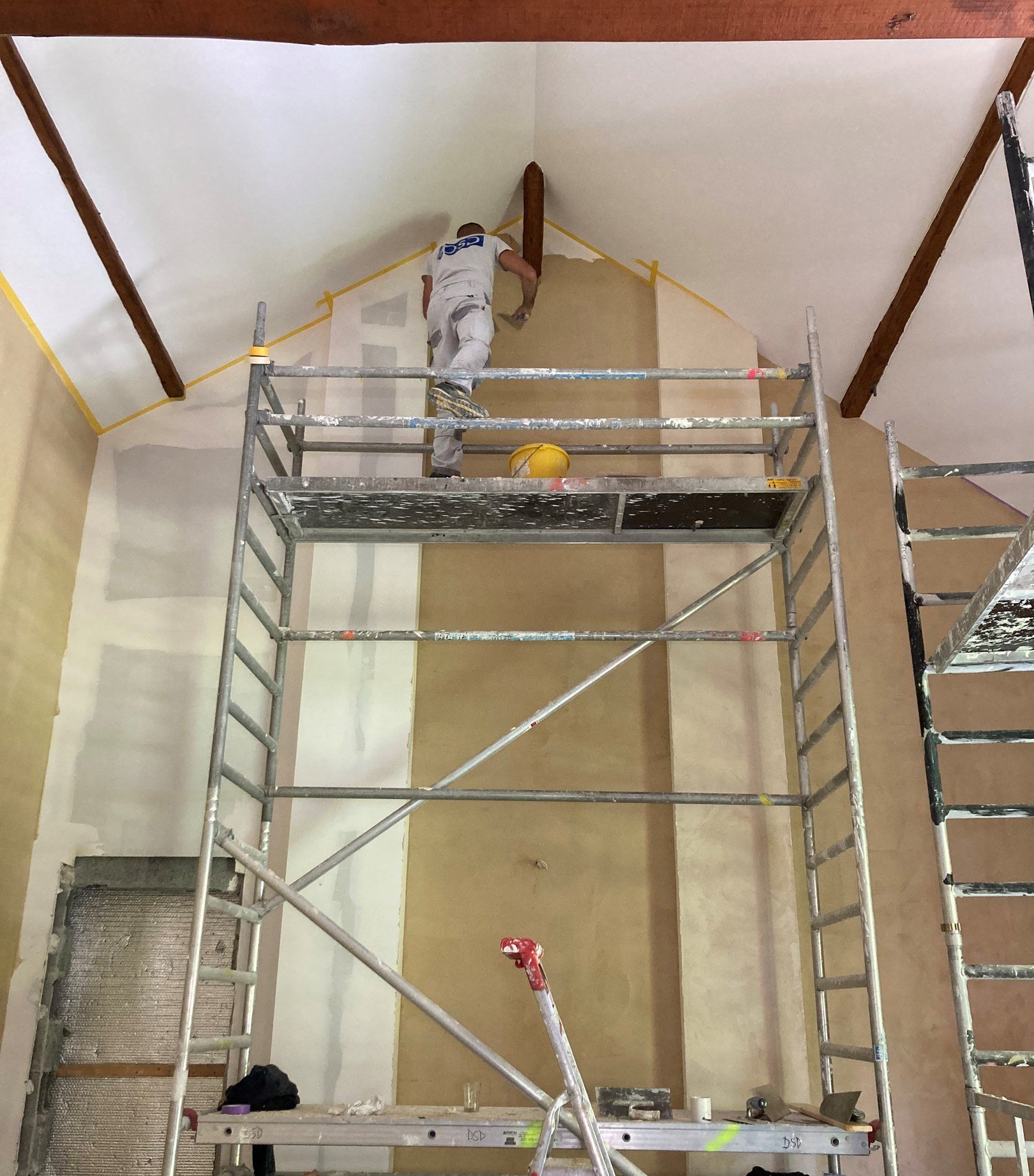 Ouvrier DSD SA sur échafaudage lors d'une rénovation intérieure avec enduits en plâtre à Genève