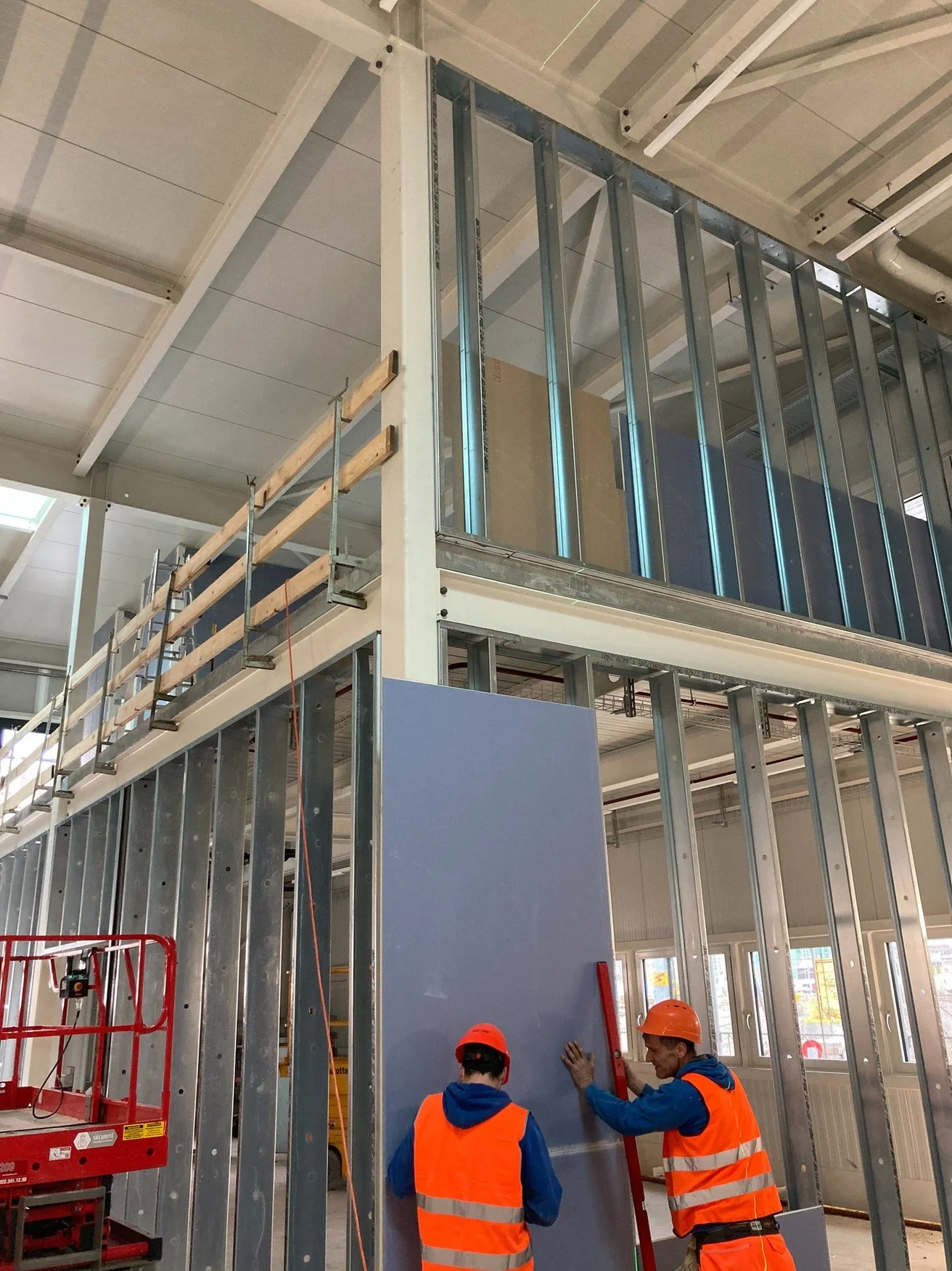 Ouvriers DSD SA posant des plaques de plâtre sur ossature métallique lors d'un chantier de construction neuve à Genève
