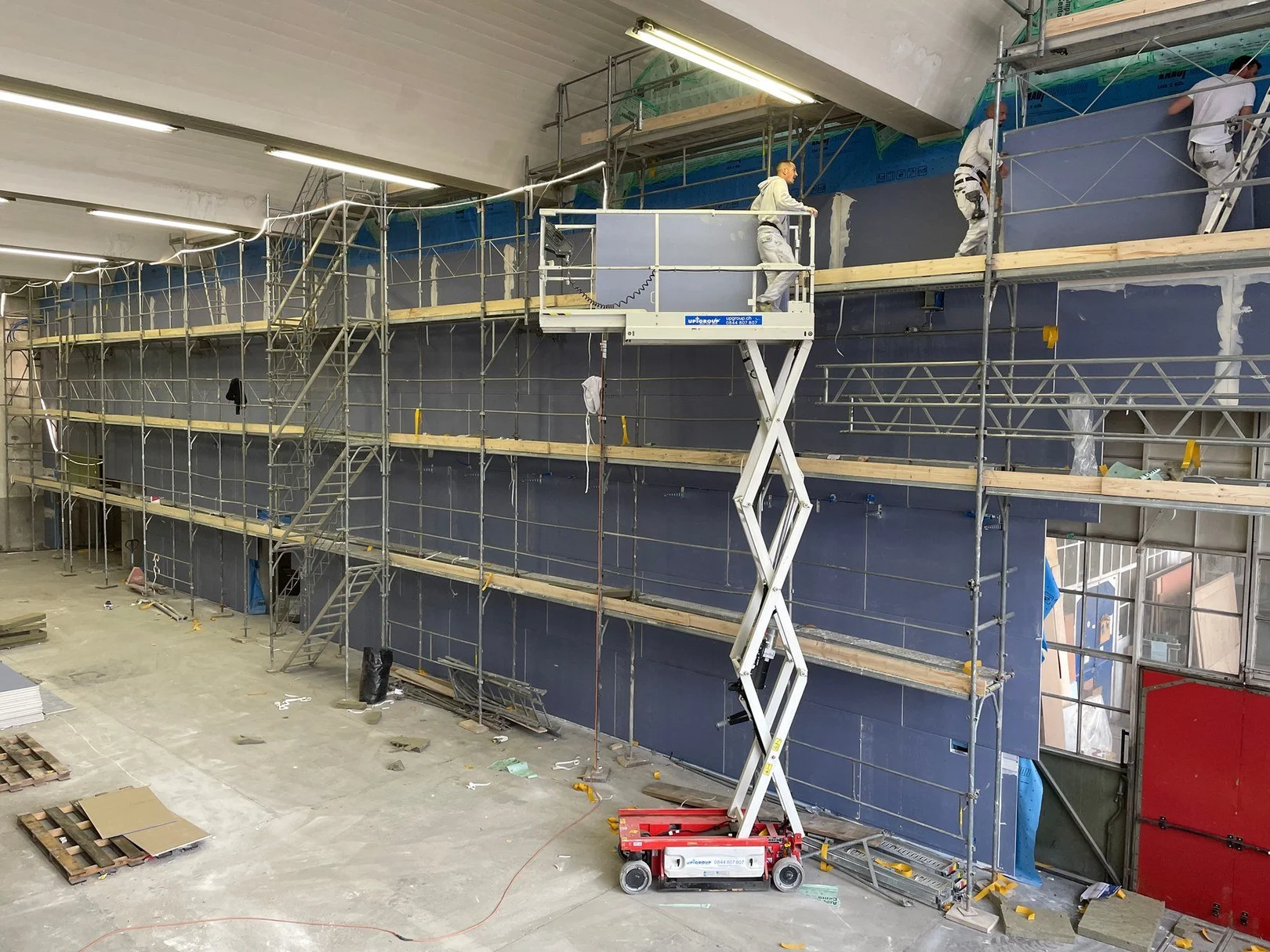Pose de panneaux acoustiques sur cloisons de grande hauteur lors d'un chantier DSD SA à Genève