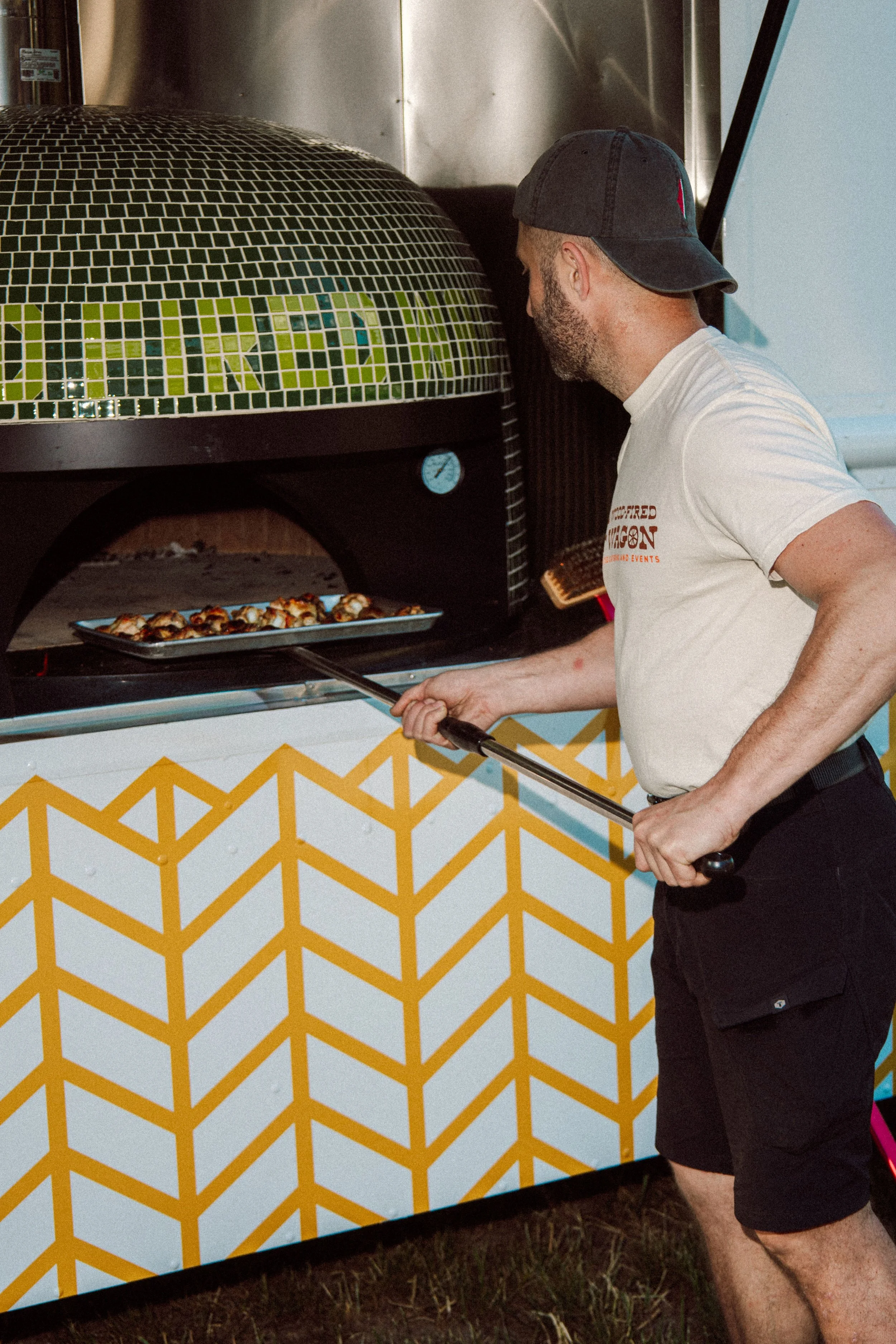 Chef/Owner Will Brown working the wood fired pizza oven, making a pizza margherita.