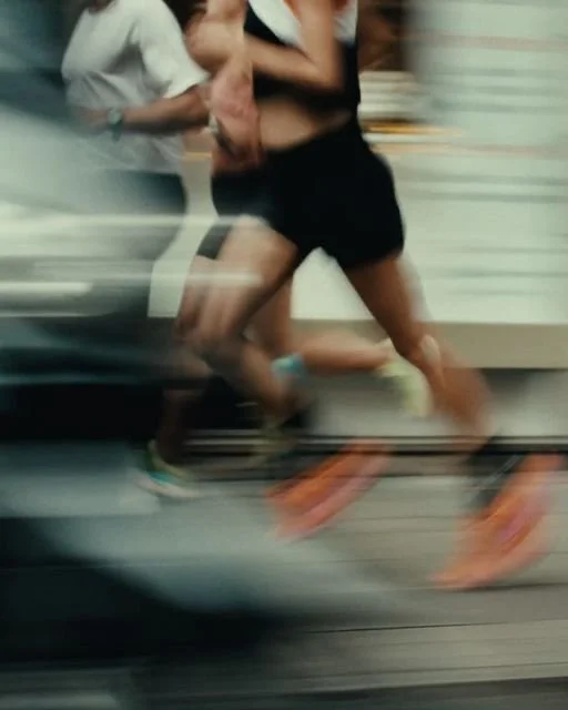 Two runners running on a treadmill, motion blur shows movement, with only their lower bodies visible.