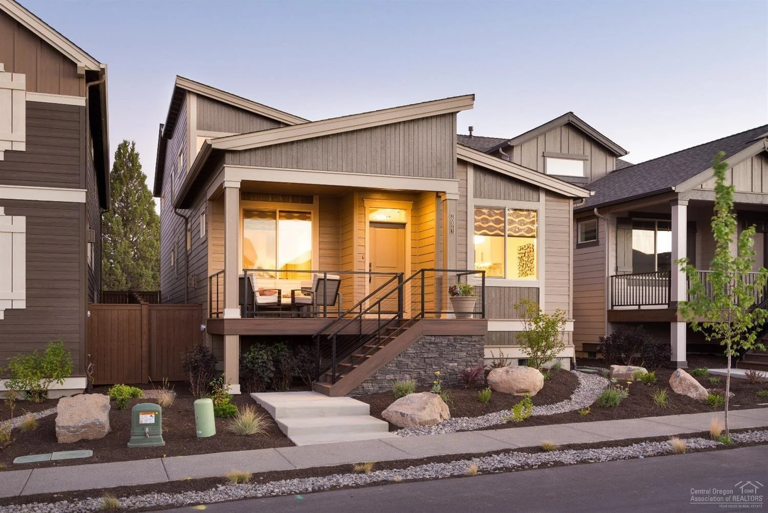 Central Oregon home with a warmly lit front porch at dusk