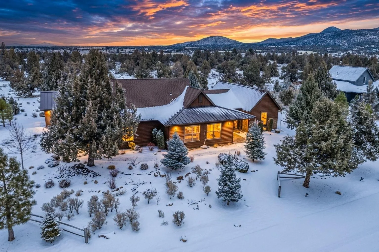 Snow-covered Central Oregon home among trees at sunset