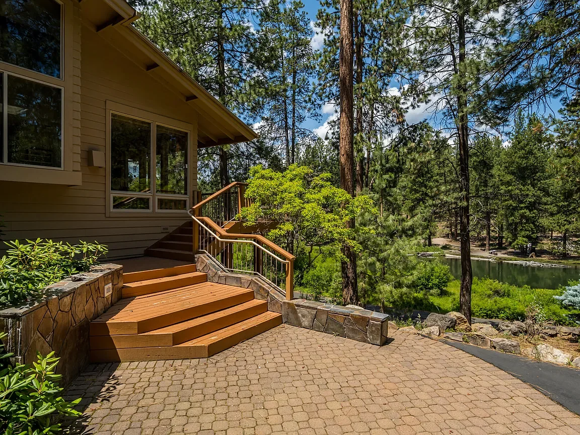 Central Oregon home with a wood deck among pine trees beside a river