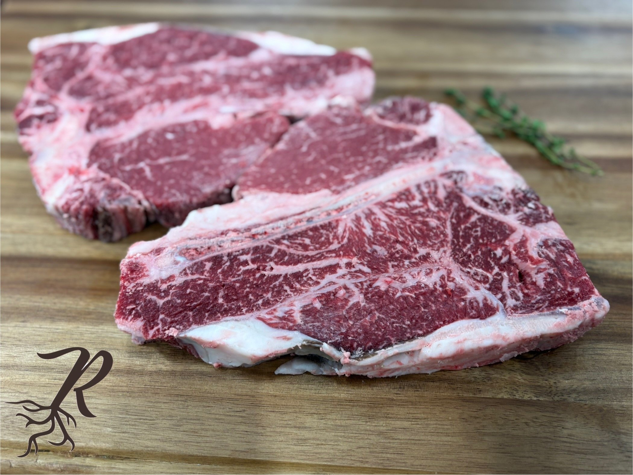three raw beef ribeye steaks with marbling on a wooden cutting board