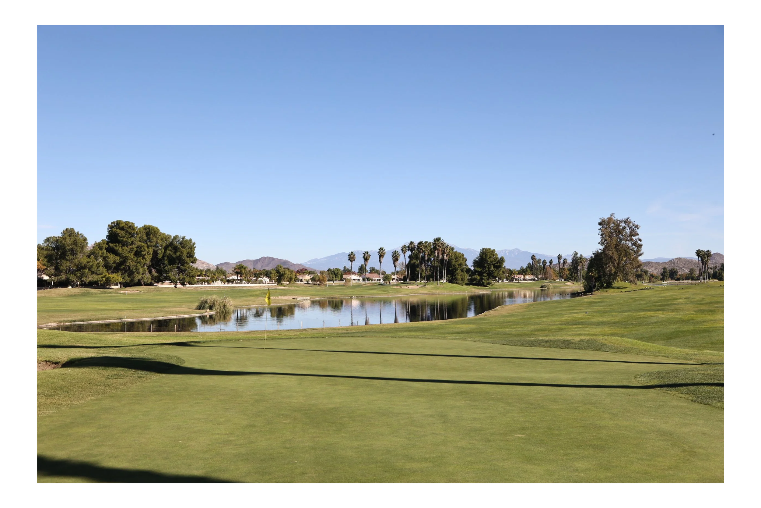 Menifee Lakes Country Club putting green with a lake and scenic mountain scape