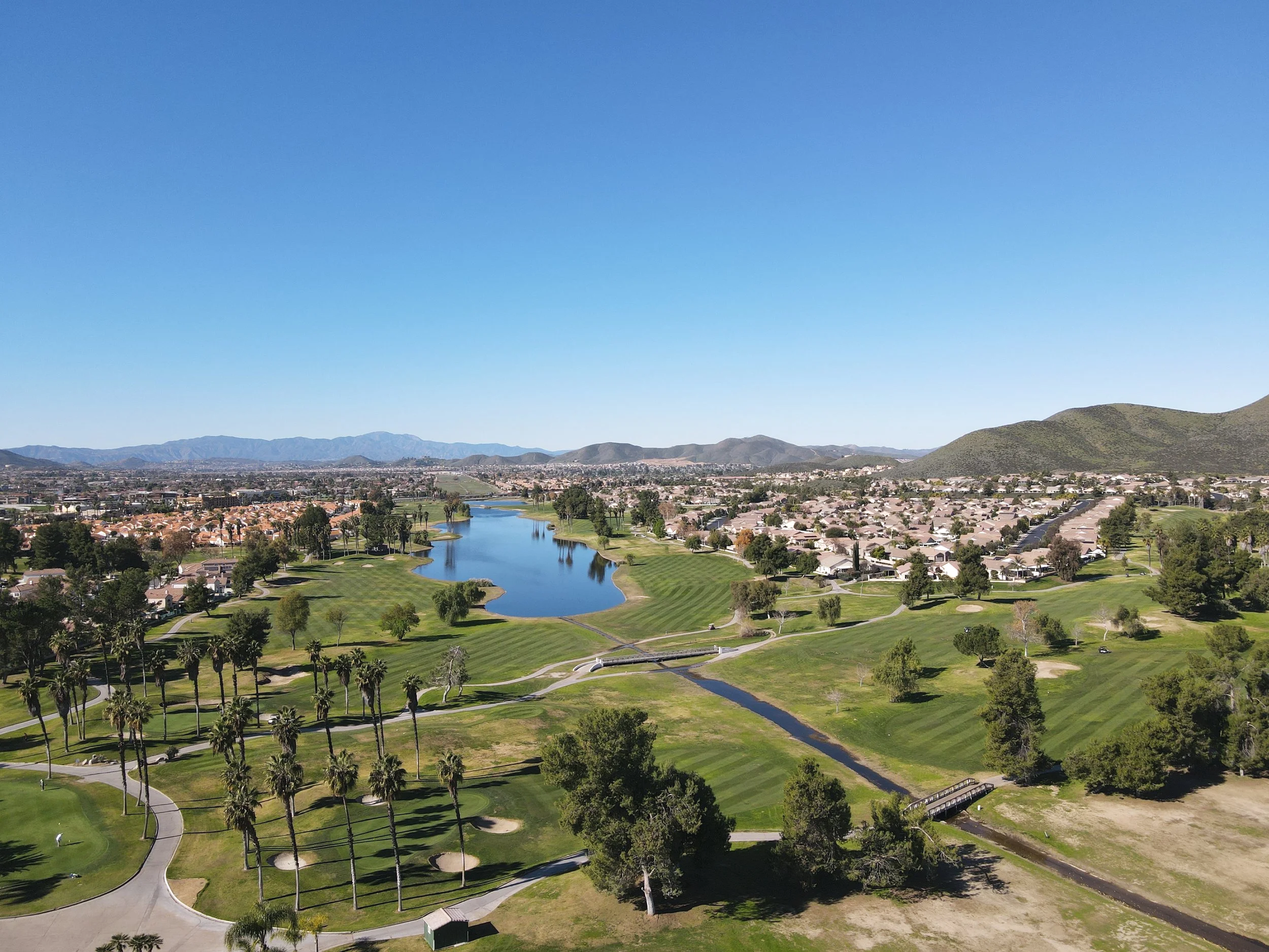 Aerial photograph of Menifee Lakes Country Club Palms Course with mountain scenery, a golf course and a lake
