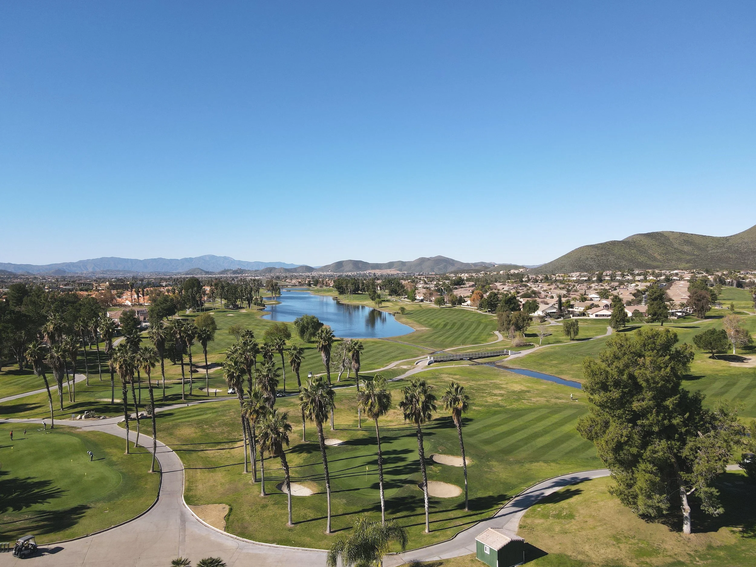 Aerial photograph of Menifee Lakes Country Club Palms Course with mountain scenery, a golf course and a lake