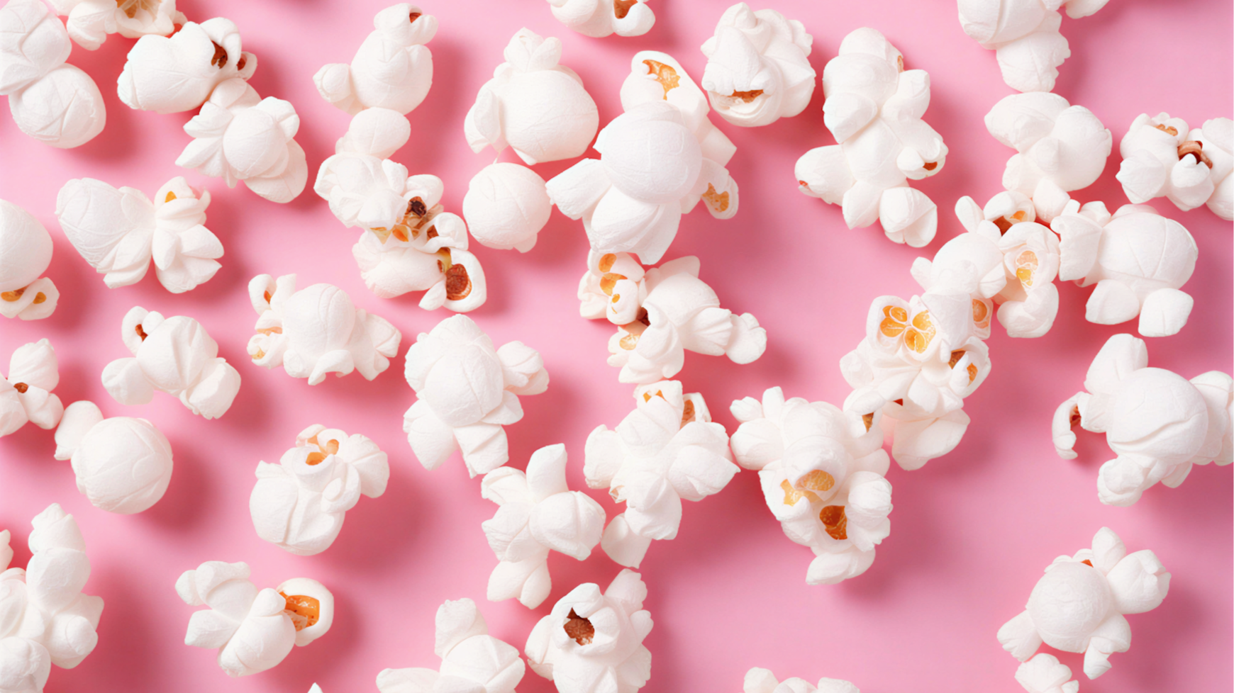 Popcorn scattered on a pink background.