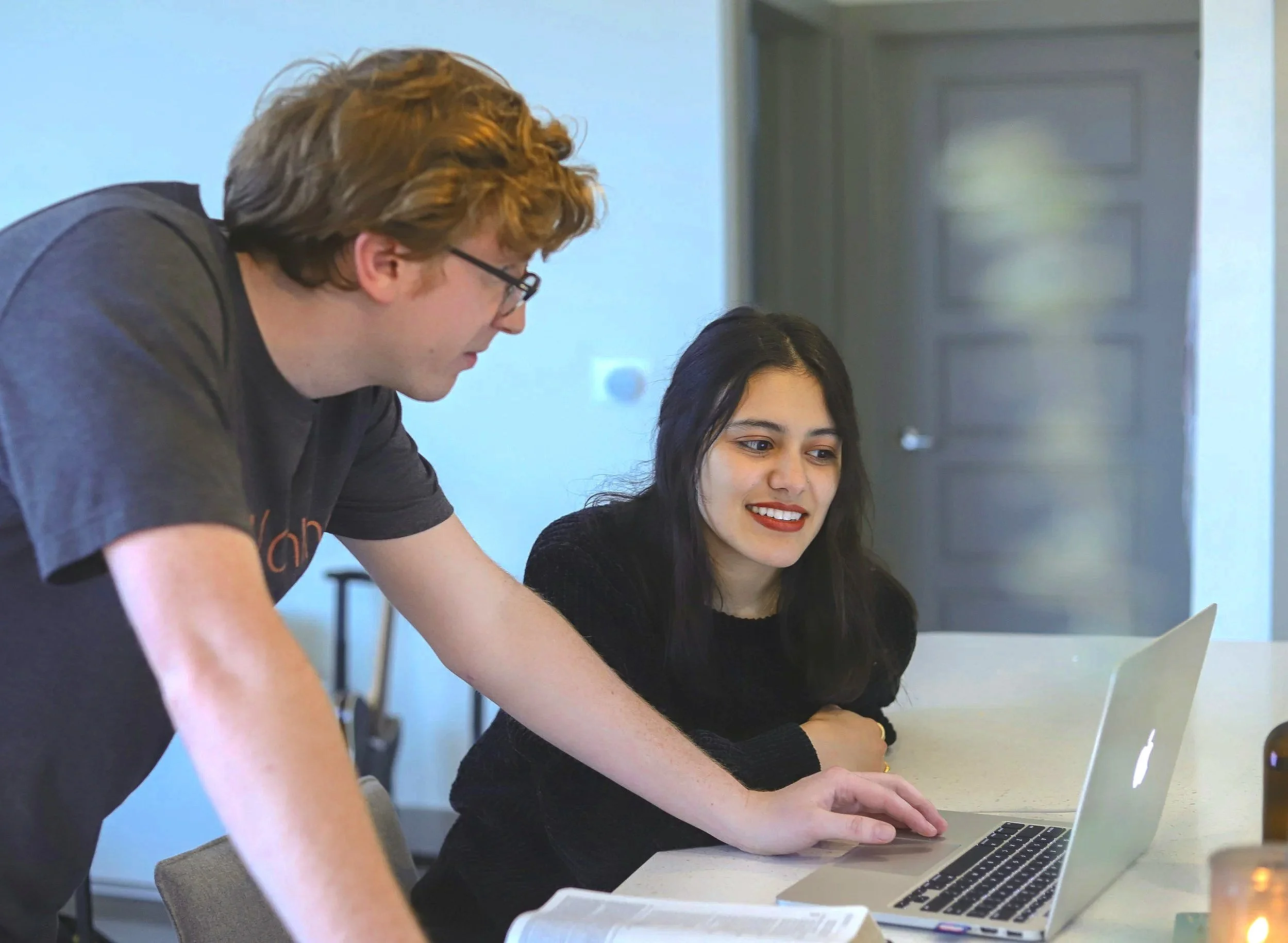 Teacher talking to a high school student at her computer 