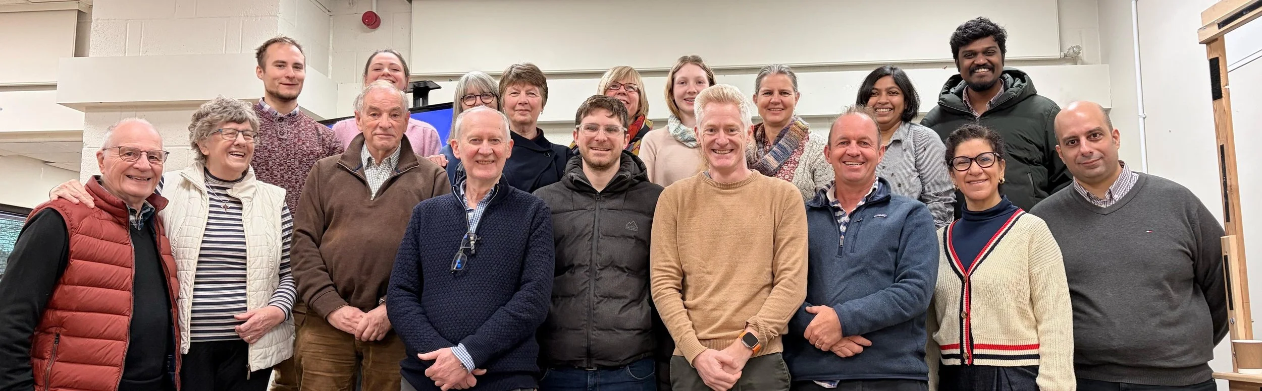 Group of people smiling, gathered indoors.