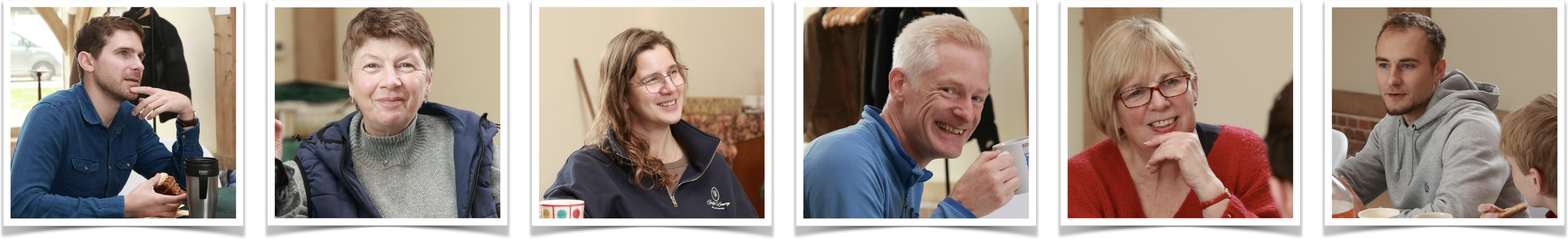 Group of six people sitting at a table, smiling and conversing in a cozy indoor setting.