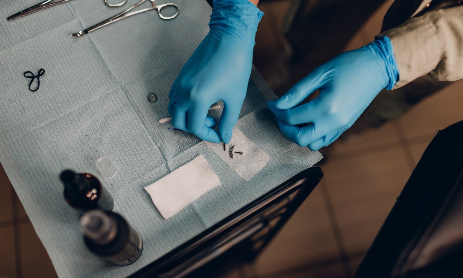 Professional piercer preparing sterile tools and jewelry for a body piercing procedure
