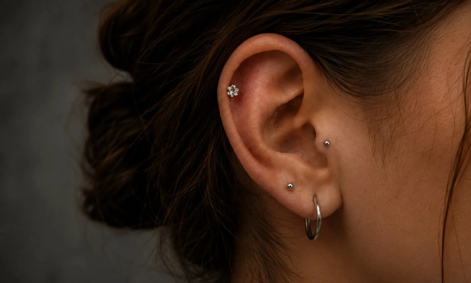 Ear featuring a tragus piercing, helix piercing, and lobe jewelry in a professionally curated ear design.