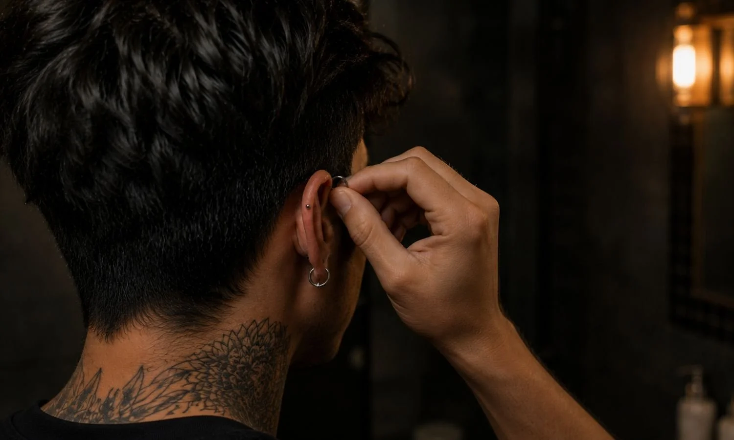 Person touching a healing cartilage piercing, demonstrating how frequent handling can irritate the piercing and contribute to piercing bumps during the healing process.