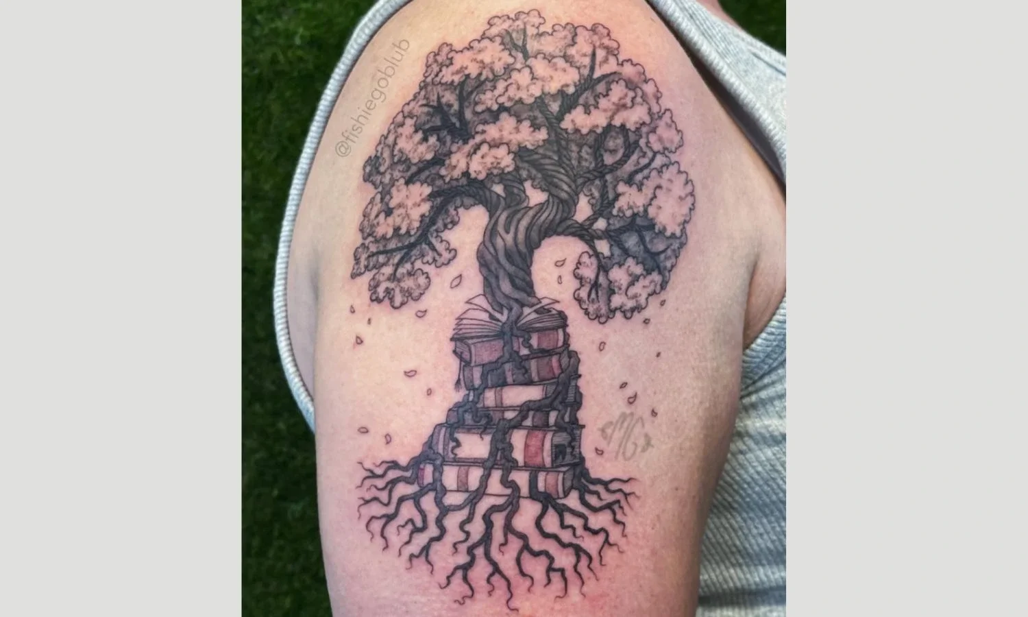Tree of life tattoo featuring a detailed trunk, spreading roots, and flowering branches on the upper arm.
