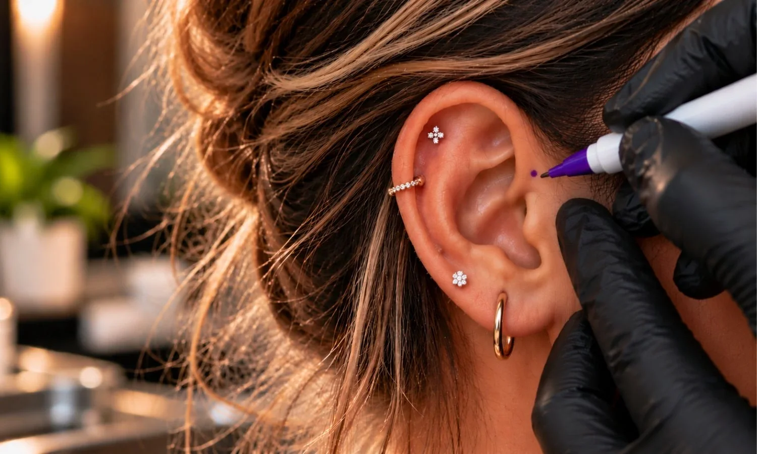 Professional piercer marking an ear to determine the placement of a new ear piercing before the procedure.