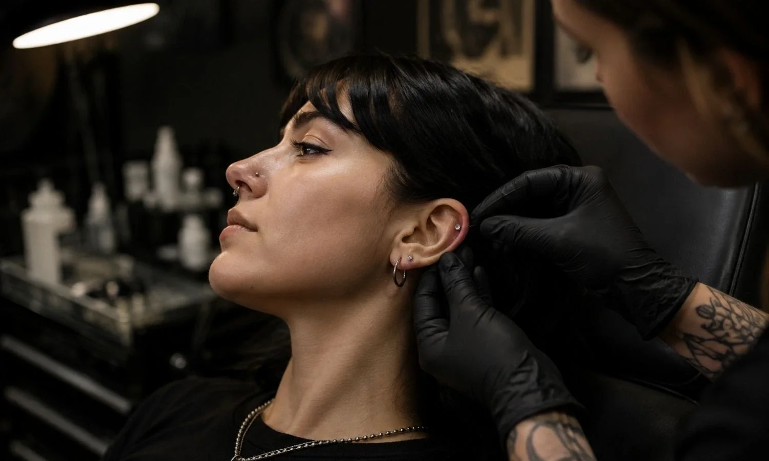 Piercer positioning jewelry on a client's ear while discussing an ear piercing placement