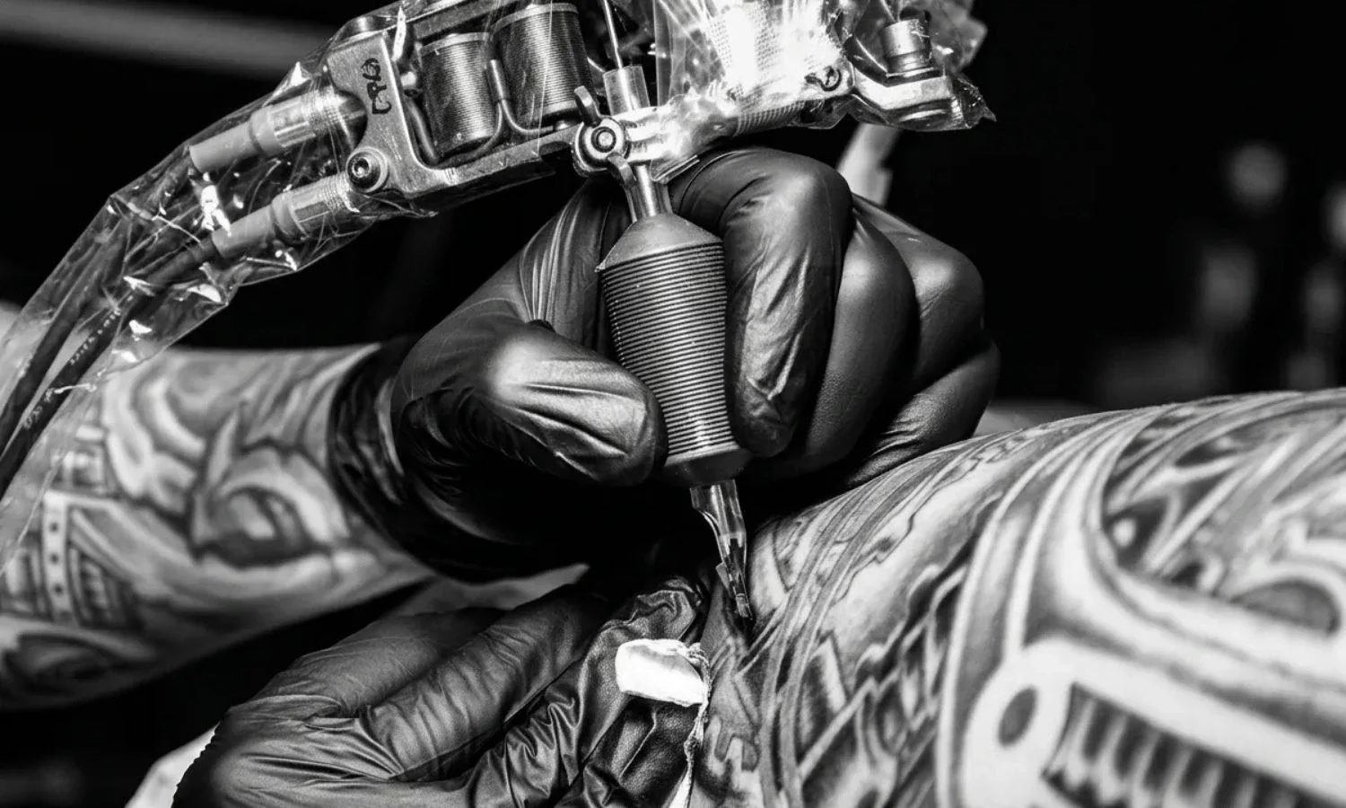 Tattoo artist using a tattoo machine while working on a client’s arm