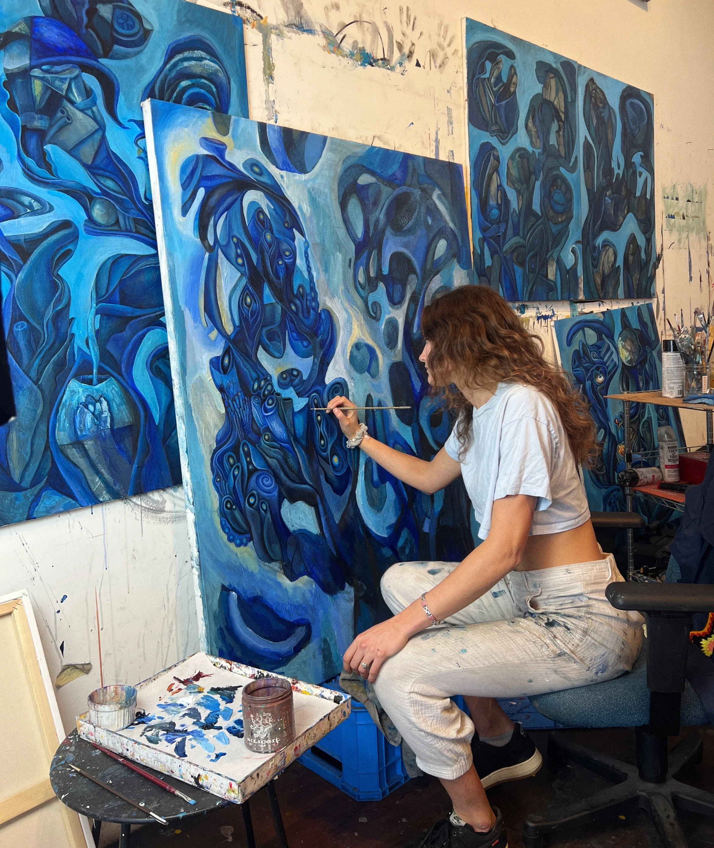 zoe rose painting blue cosmic forms in studio.webp