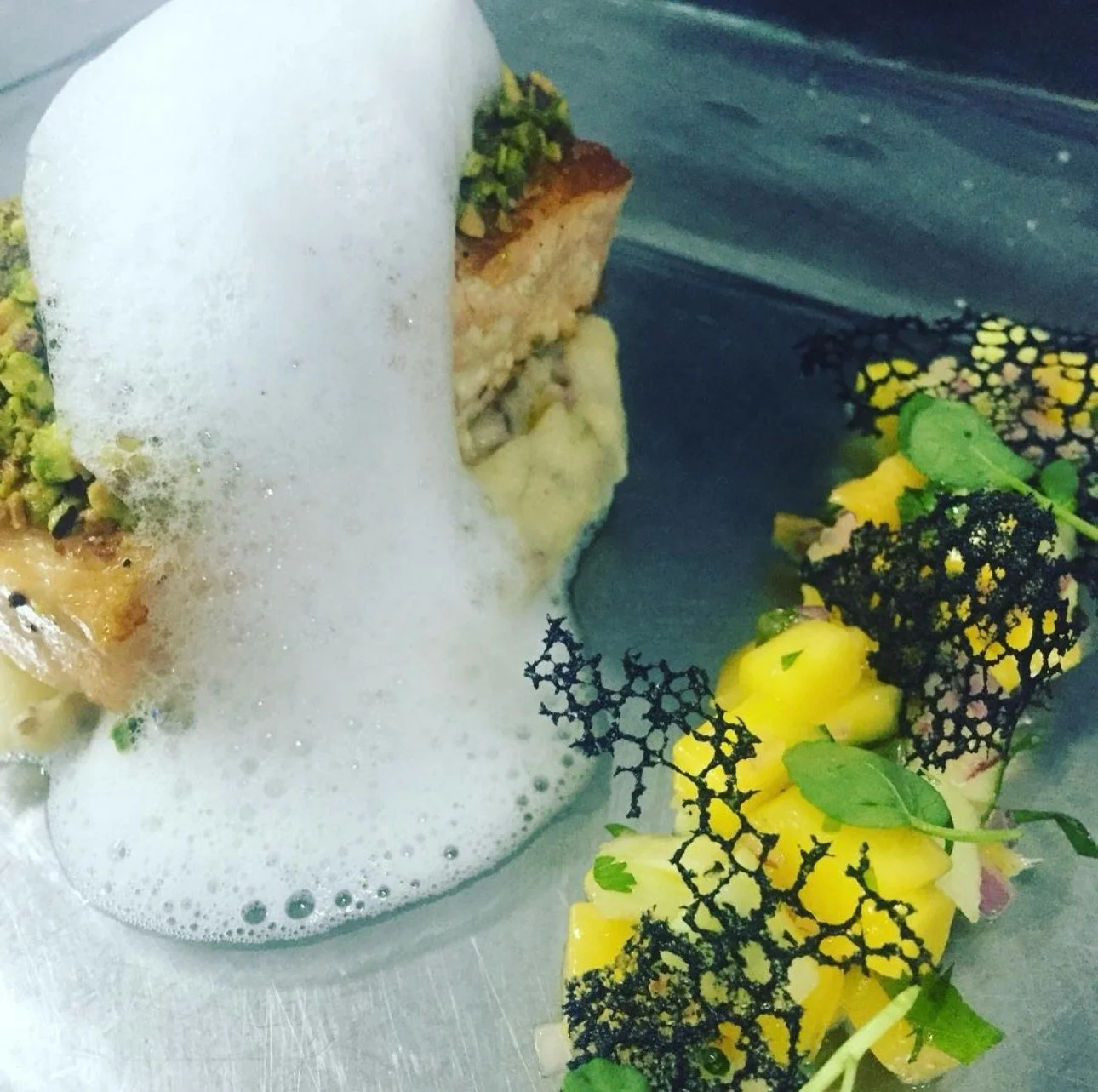 Salm&oacute;n encostrado en pistachos, sellado con precisi&oacute;n para conservar su jugosidad y coronado con una costra crocante que aporta textura y car&aacute;cter. Lo acompa&ntilde;amos con pur&eacute; r&uacute;stico de papas, cremoso y reconfor