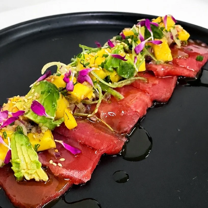 Tiradito de at&uacute;n acompa&ntilde;ado de ensalada fresca de mango, palta y brotes verdes, terminado con leche de tigre y notas c&iacute;tricas que realzan cada corte. Frescura, acidez y equilibrio en un plato pensado para despertar el paladar.

#