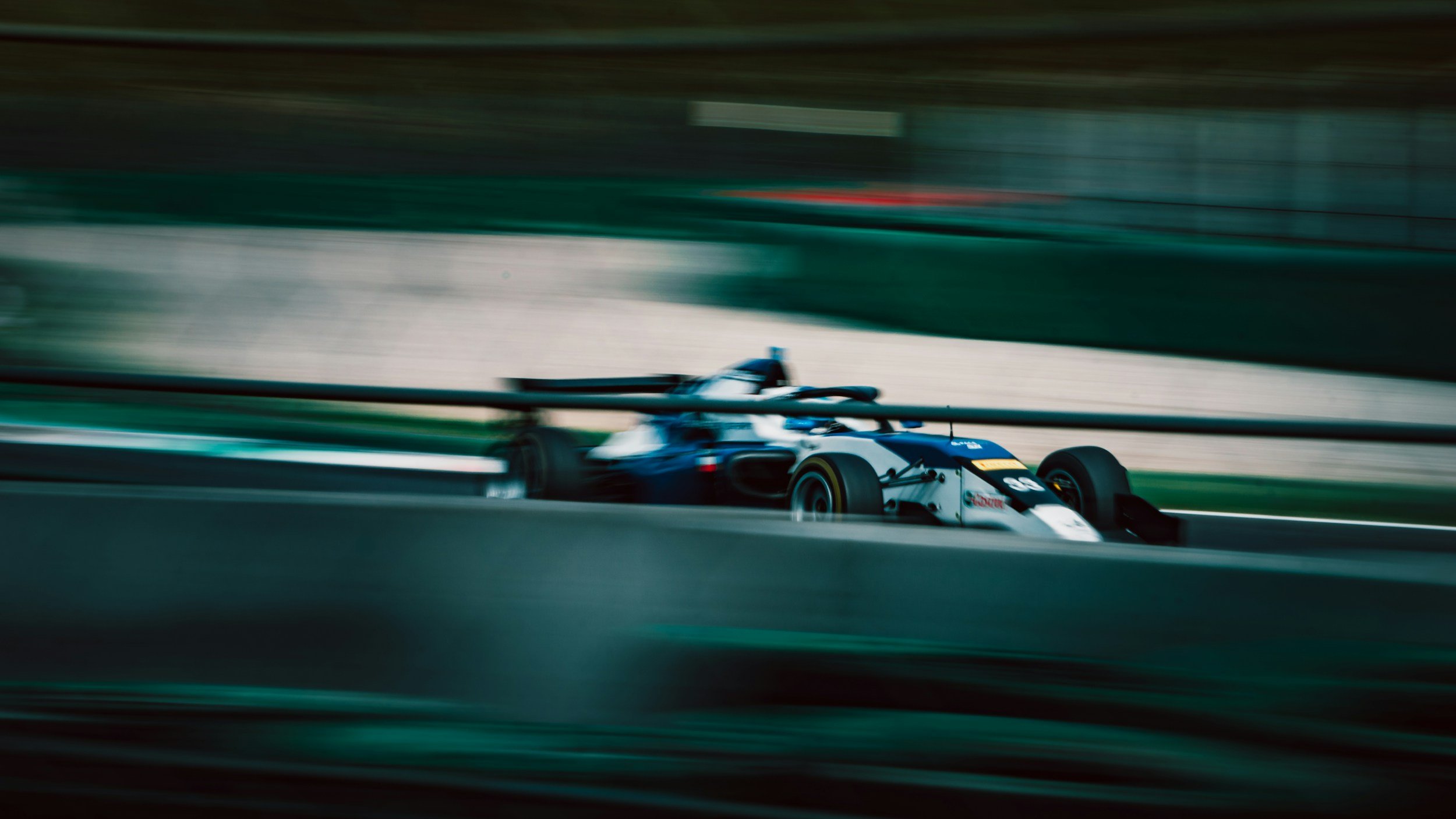 A race car moving at high speed on a race track, with motion blur showing speed and movement.