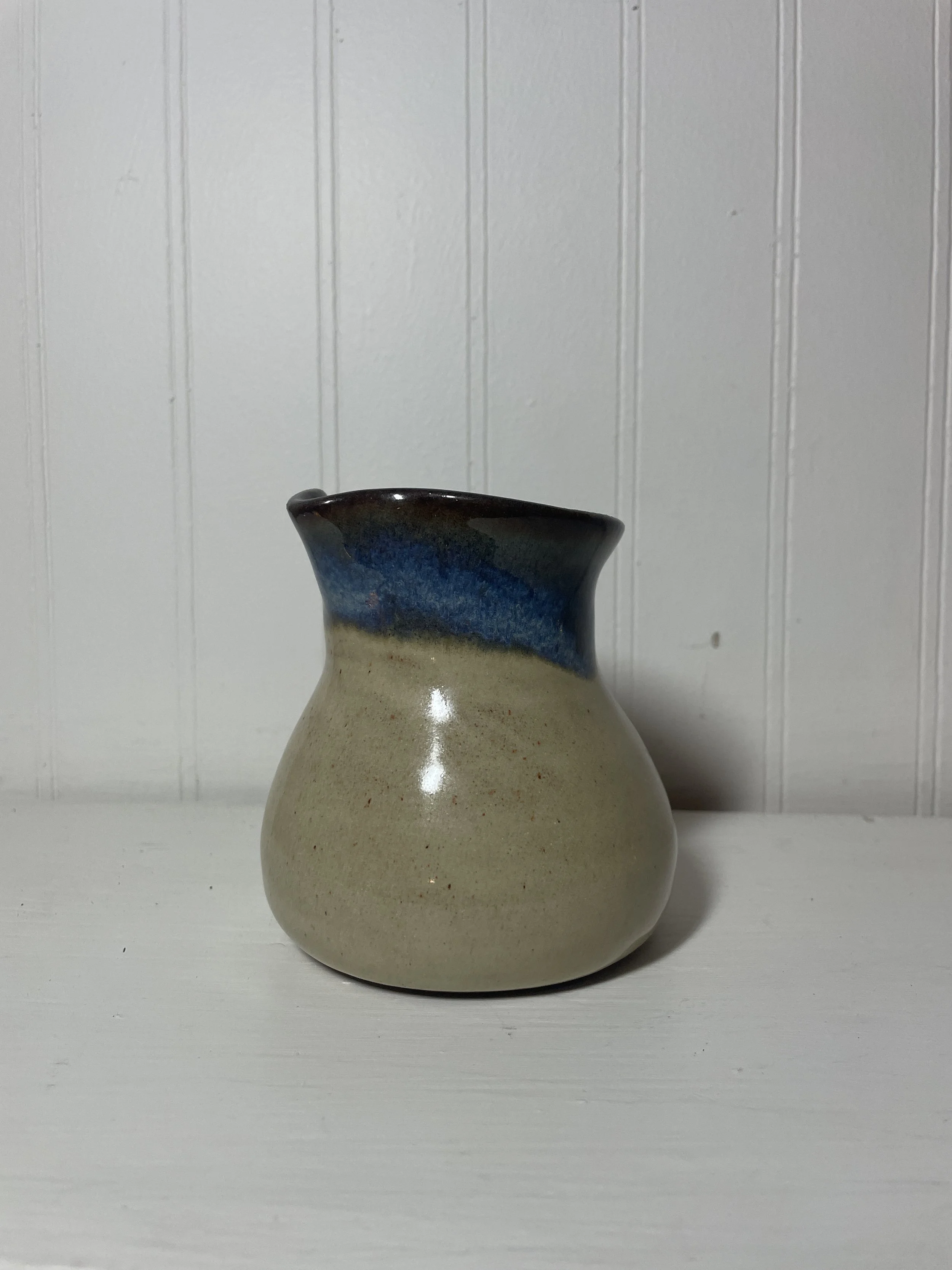 A beige and blue ceramic vase with a narrow neck and bulbous base.