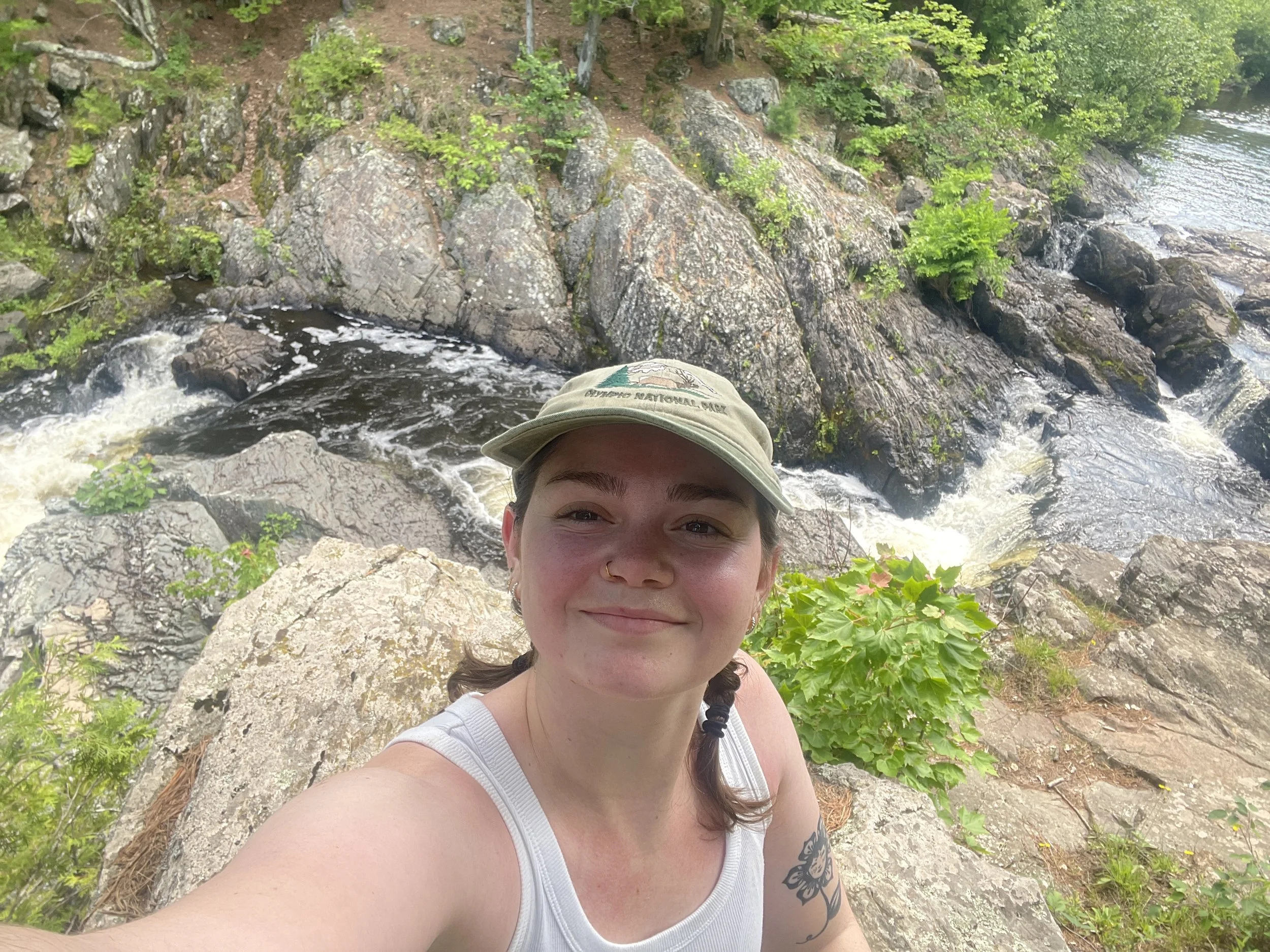 A woman with brown hair smiling for a selfie on the Dead River in Marquette, Michigan.