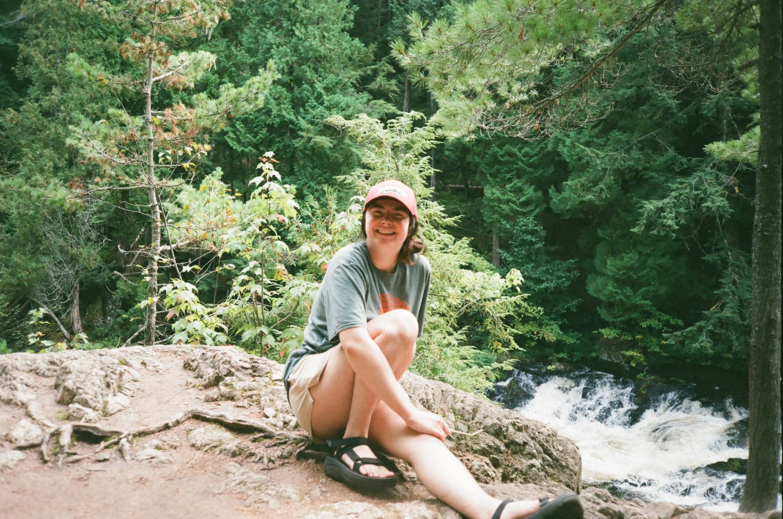 A woman sits on a large rock near Dead River Falls in Marquette, Michigan.