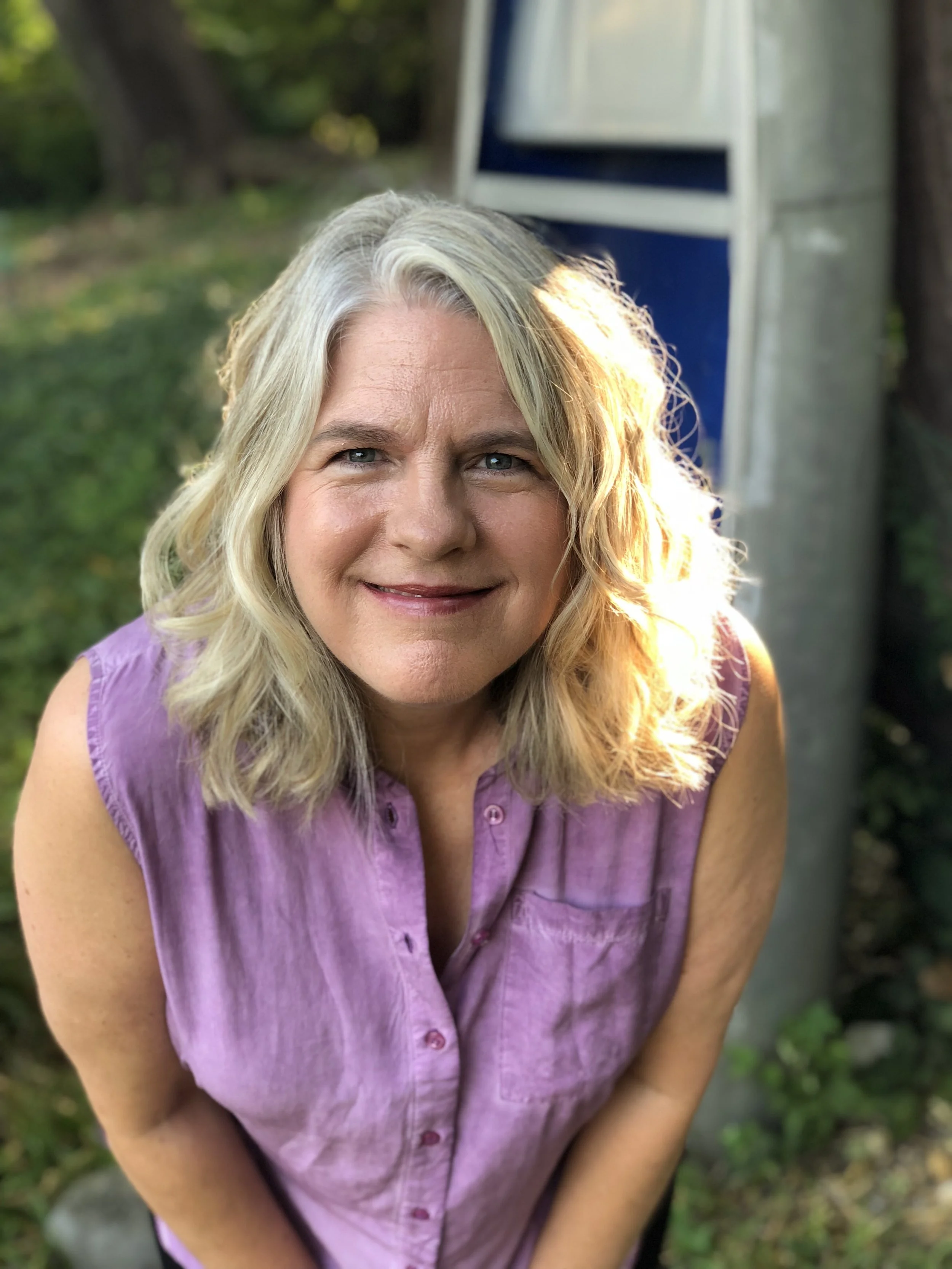 Close up headshot of Carolyn with light purple sleeveless top on.