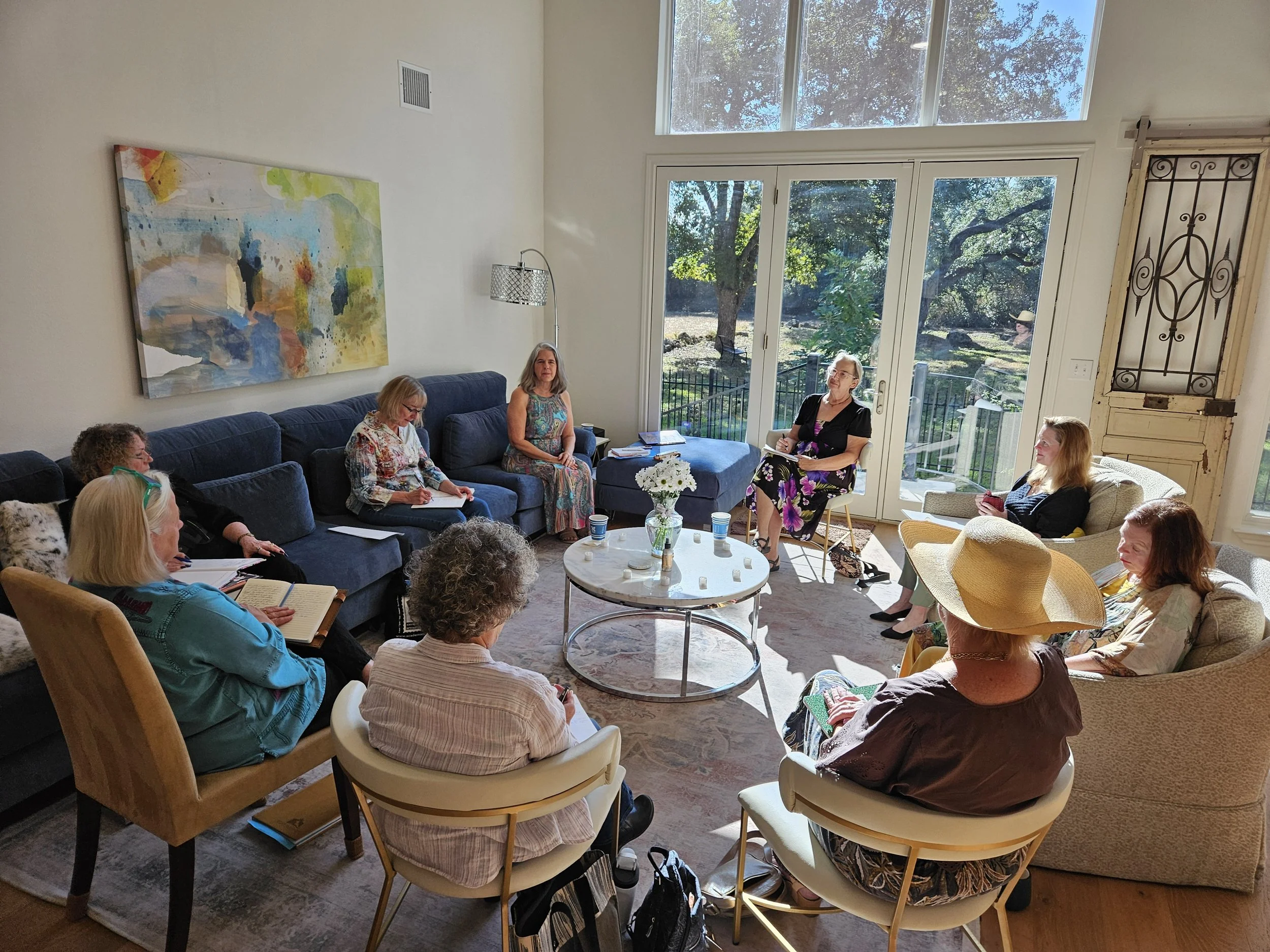 group of women sitting in a circle in the living room exchanging discussion while busy in their journals.