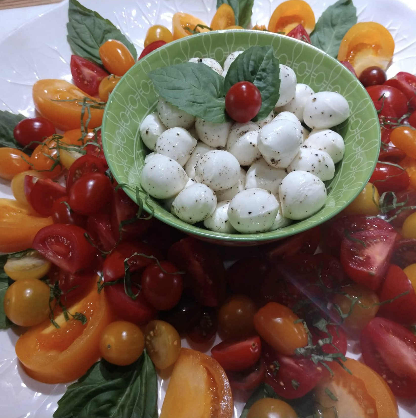 Culinary shots of mozzarella balls and cherry tomatoes, tossed in olive oil and basil.