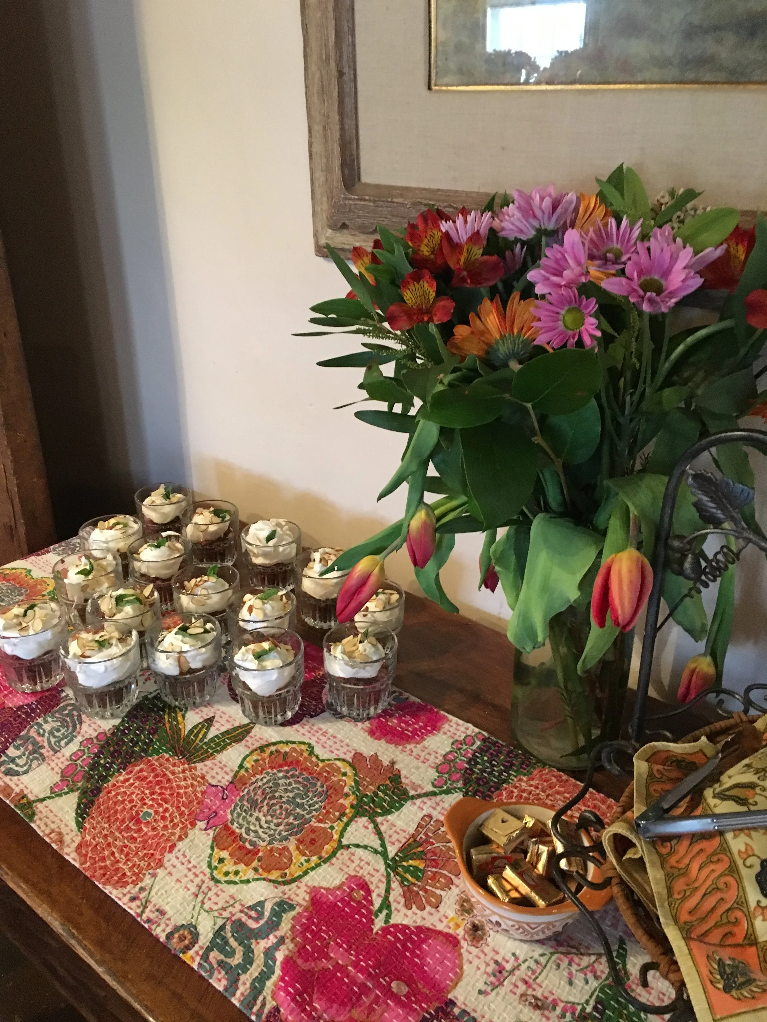 Culinary shots of table of flowers and single serve cakes.