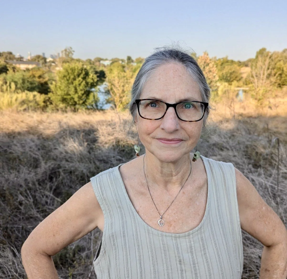 Headshot of Julie, movement lead, wearing a silver pulled back pony, dainty dangled earrings, and chic black framed glasses.
