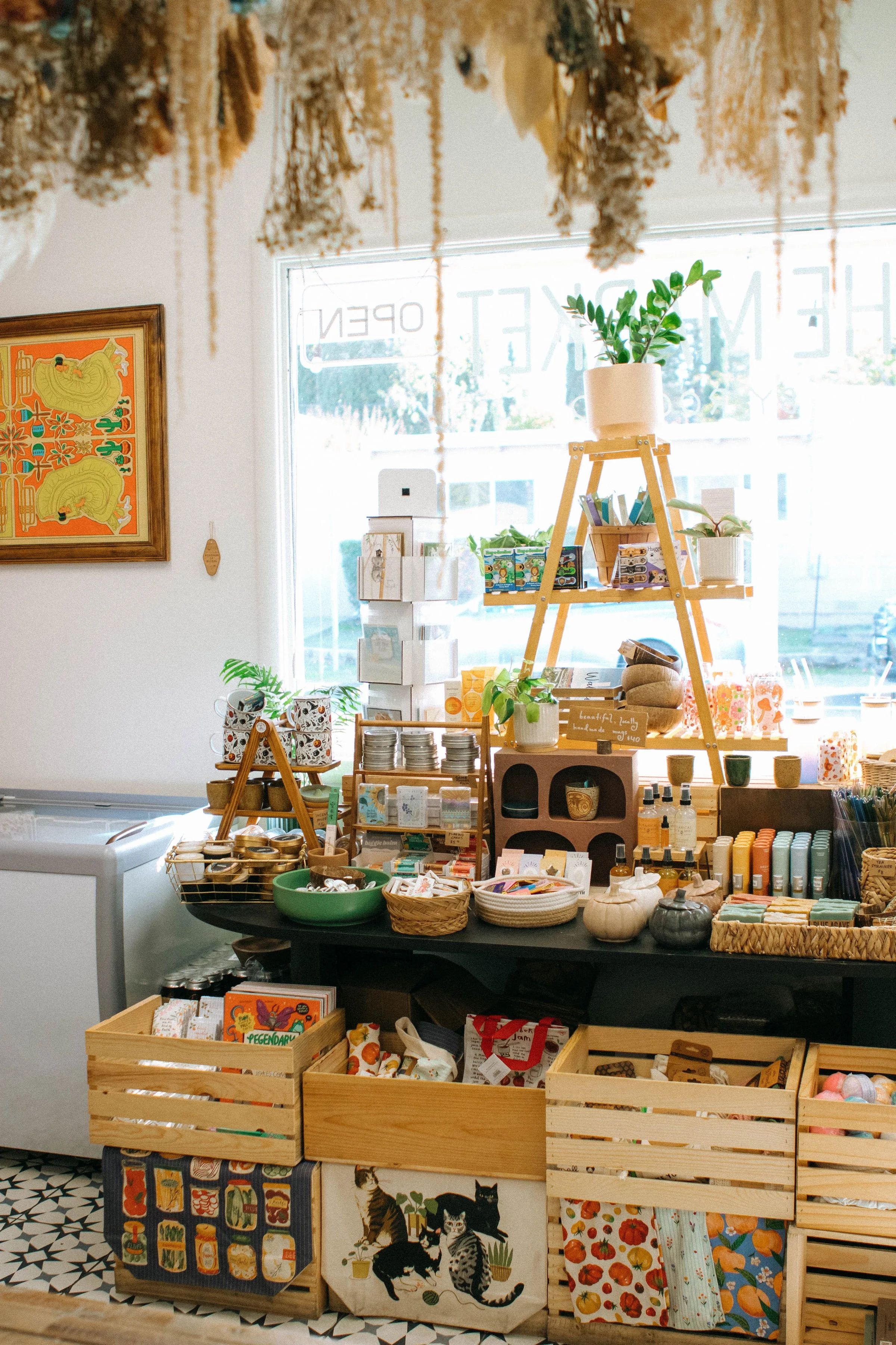 Display of various plants, candles, and small decorative items inside a store with bright natural light coming through a window.