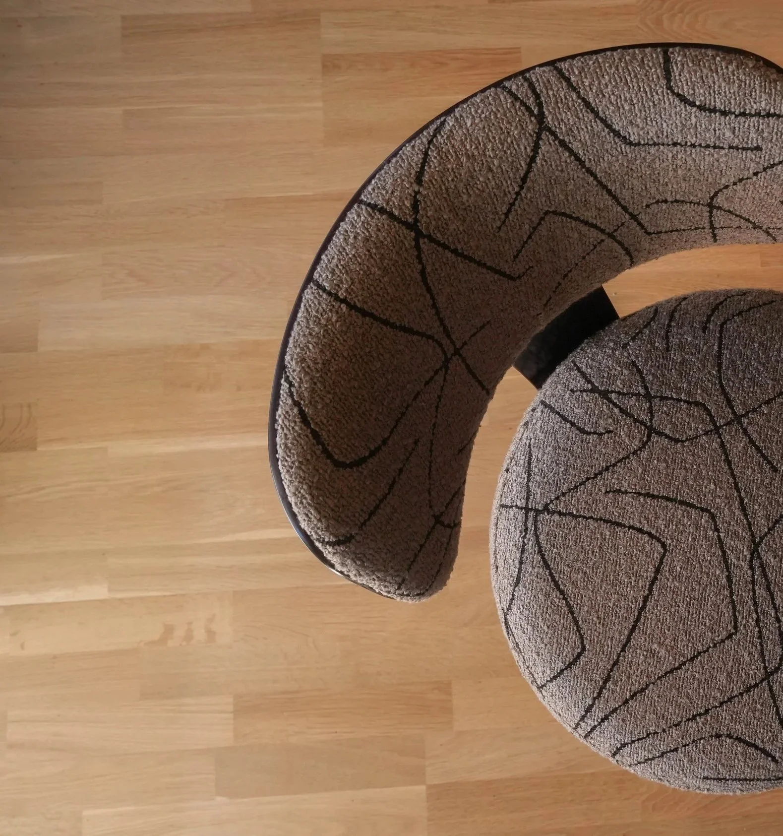 A curved, patterned sofa on a wooden floor, shown from above.