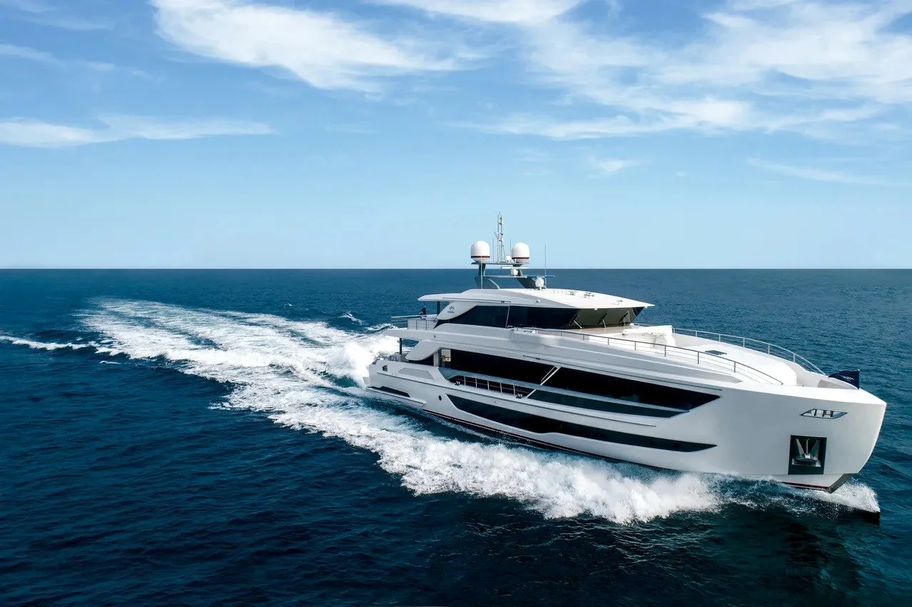 A large white luxury yacht sailing on the open ocean under a clear blue sky.