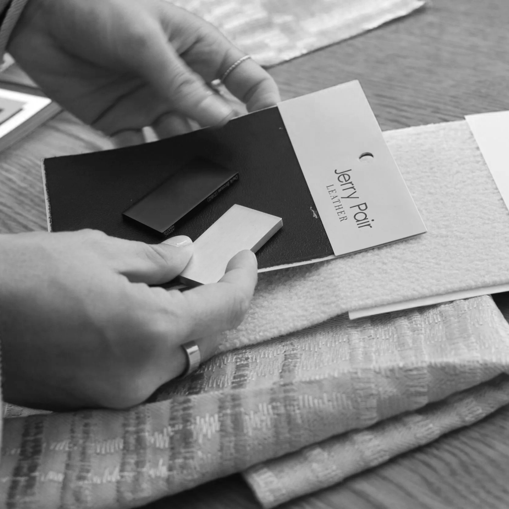 Person holding a leather sample card with fabric samples attached.