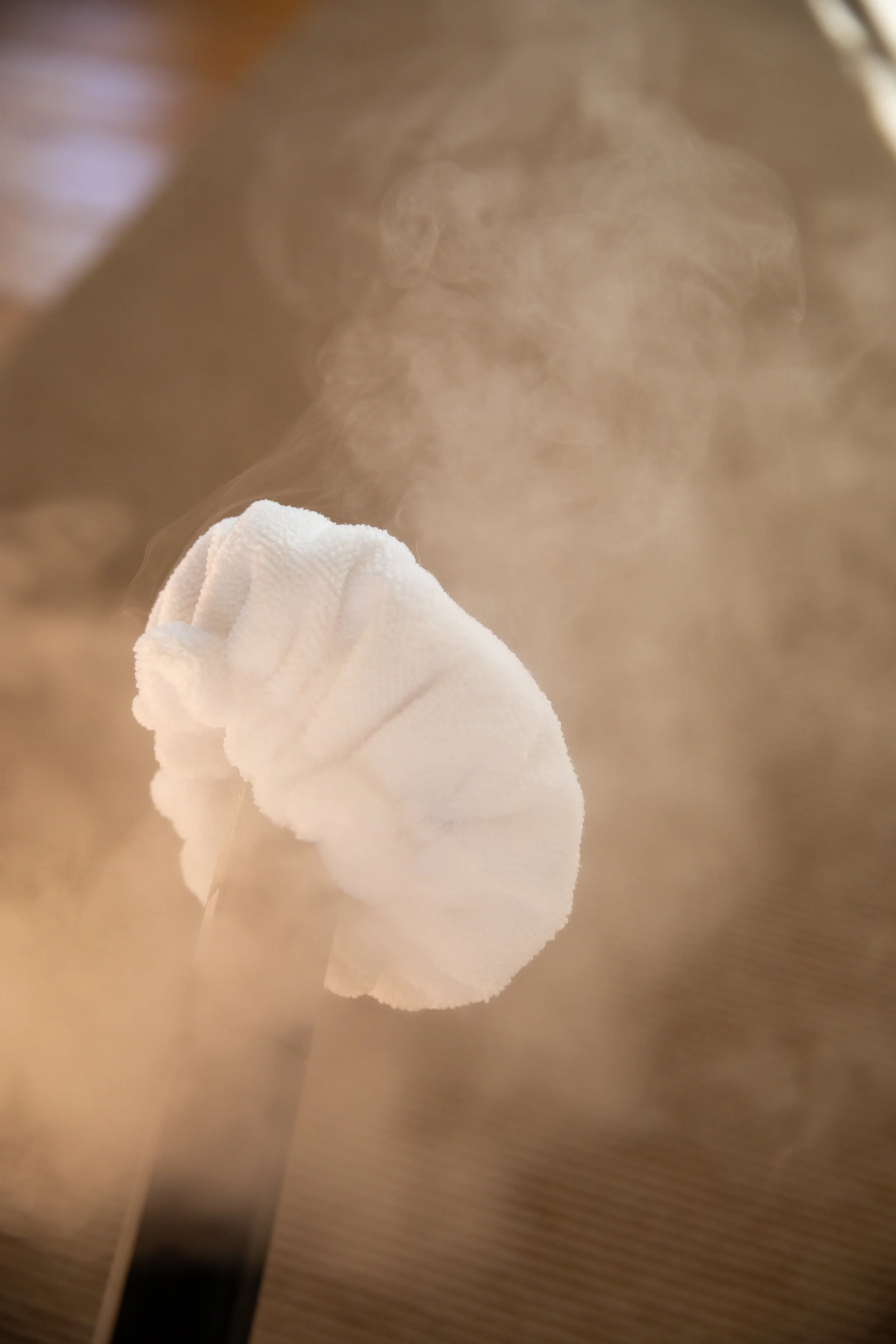 Close-up of a steam or vapor cloud rising from a white cloth-covered object or surface.