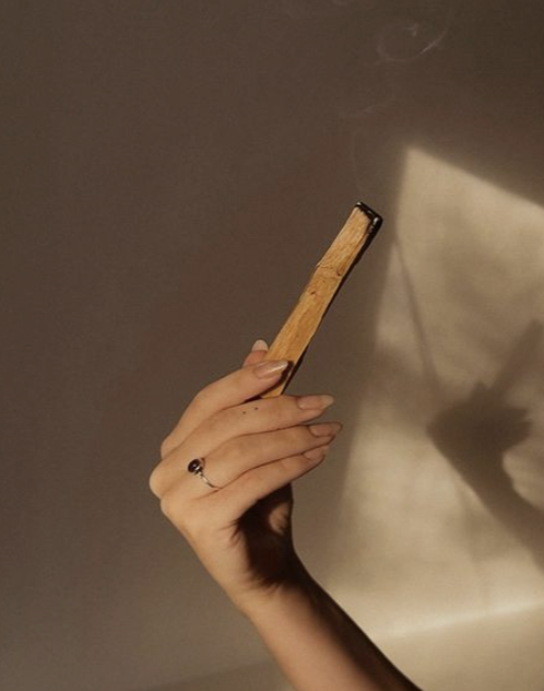 A person holding an old, worn book with a brown cover against a gradient beige background.