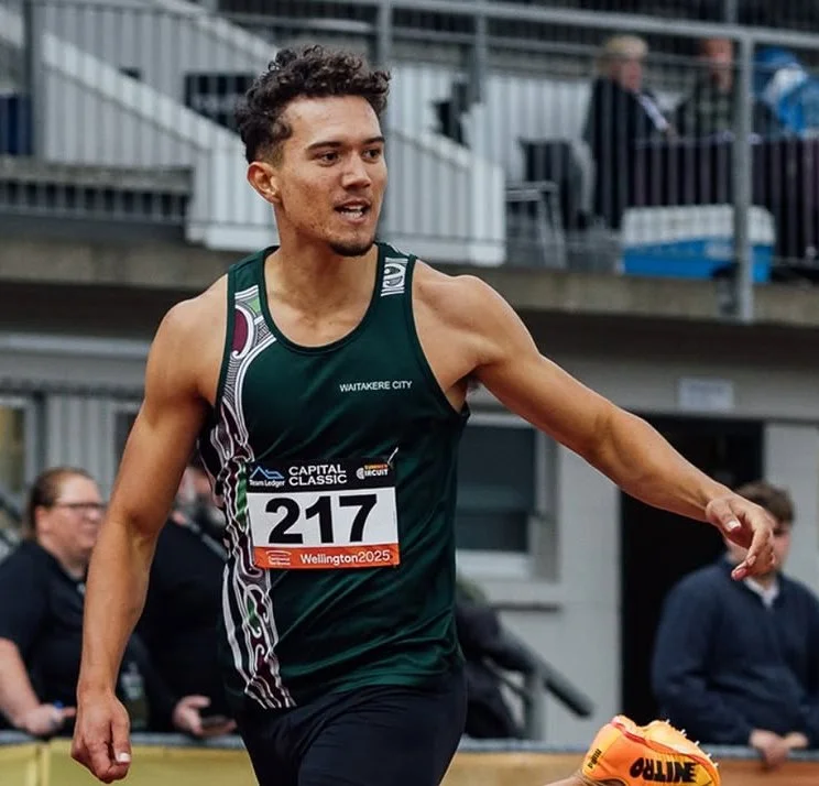 Track athlete wearing a race bib number 217, reaching out during a race, with spectators in the background.
