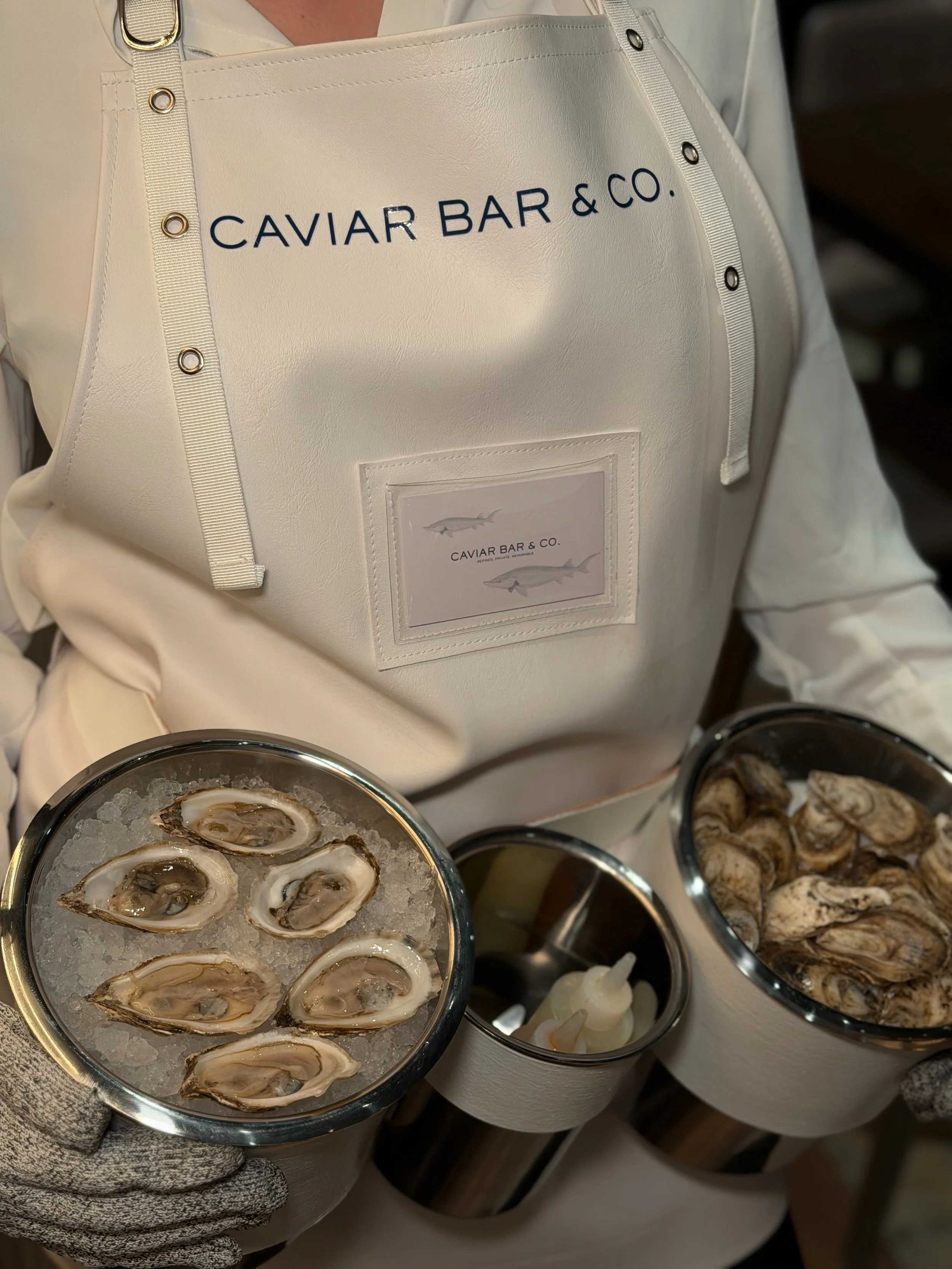 Caviar Bar & Co. Oyster shucker specialist holding oysters on ice and presenting premium interactive oyster catering experience