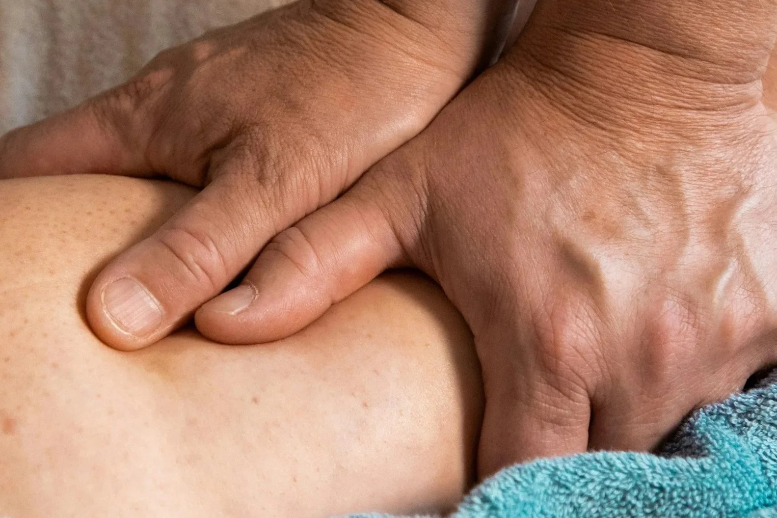Close-up of a hand applying a manual therapy technique or physical therapy or chiropractic or osteopathic or myotherapy or massage technique to a person's spine or lower back or shoulder area. Demonstration of manual therapy technique.