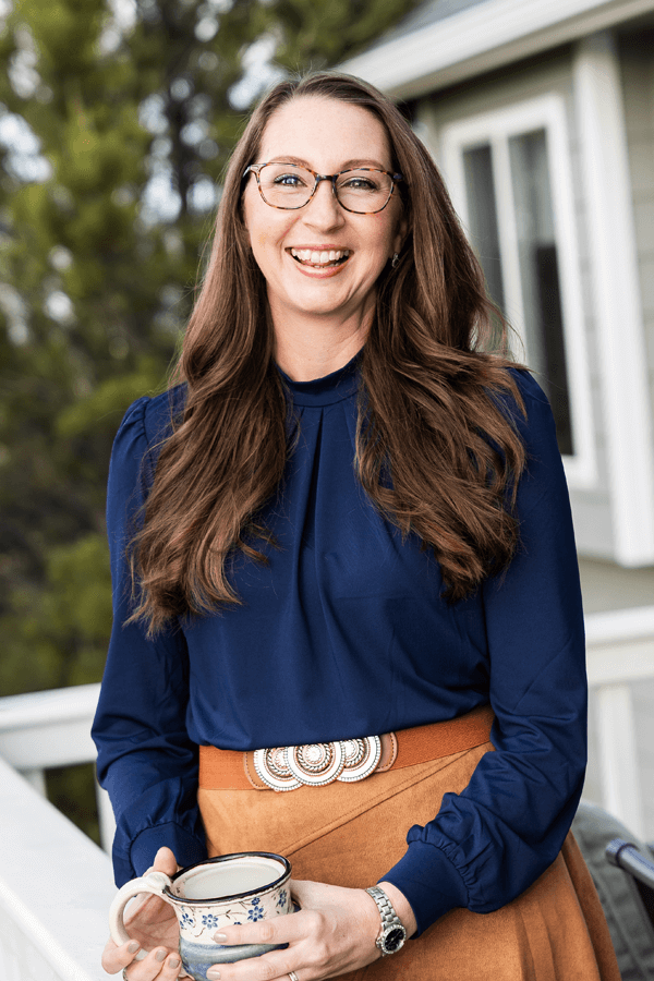 Photo of Jenn Baas leaning against porch railing smiling
