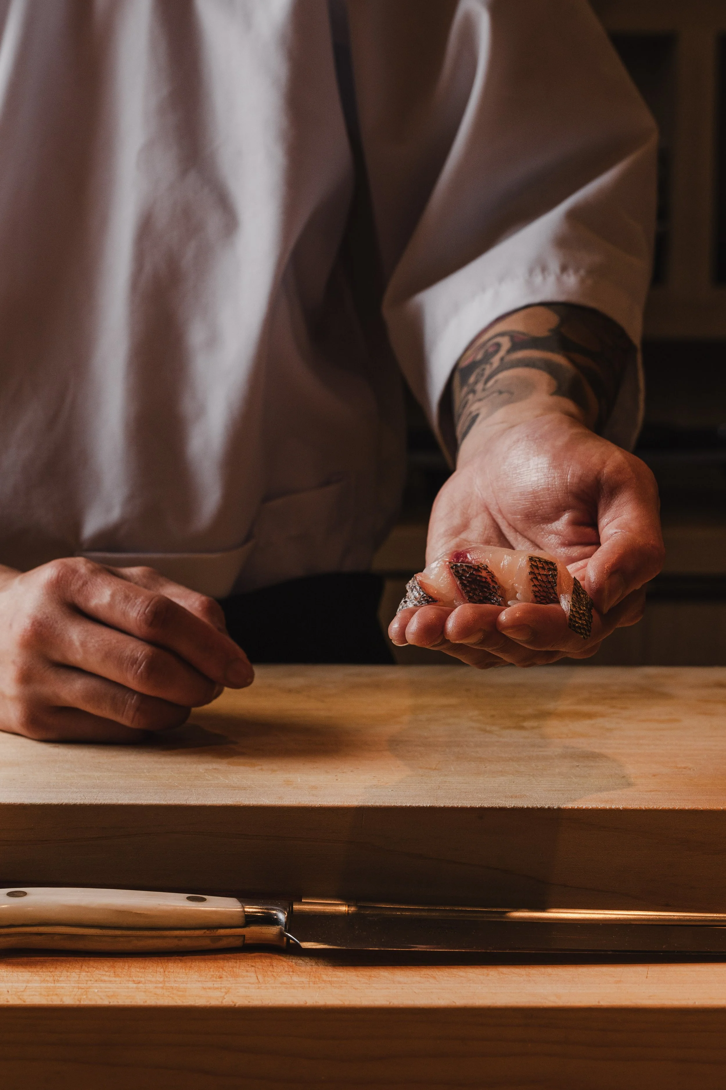 Executive Chef of Yugen in Sarasota Holds Japanese Fish Nigiri in His Hands at the Counter