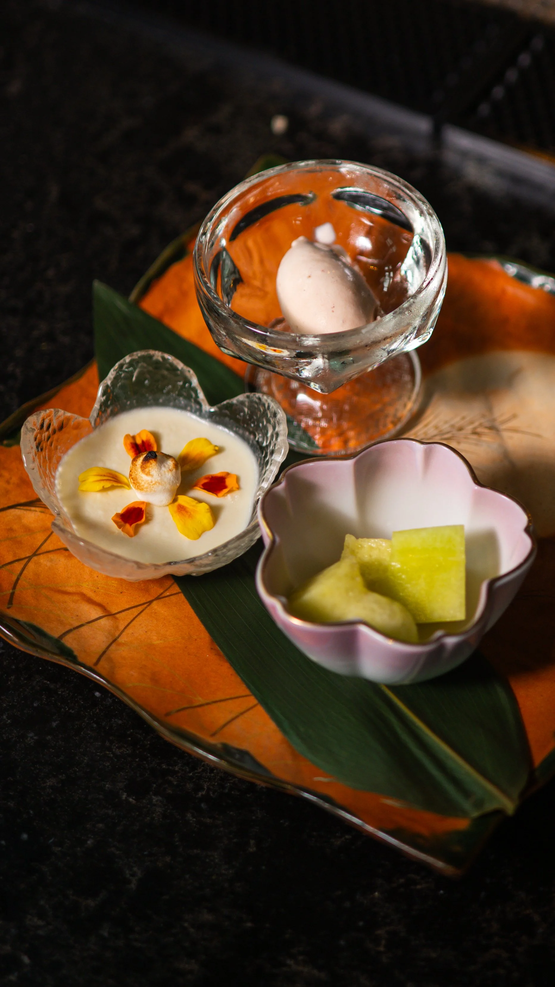 A trio of Japanese desserts at Yugen featuring seasonal melon, sorbet, and a creamy fruit custard in artisanal ceramic ware.