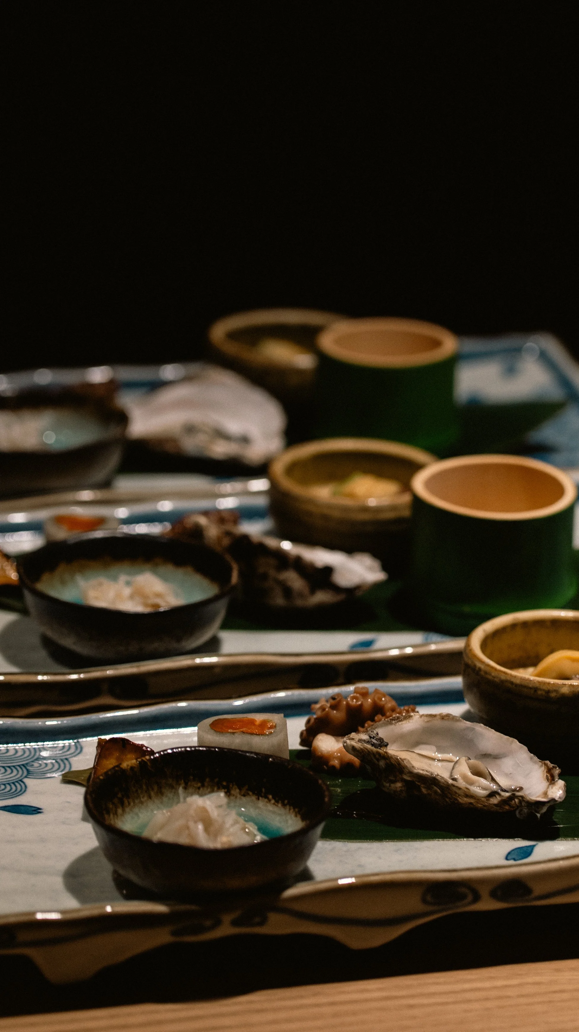 An elaborate multi-dish Hassun course at Yugen featuring fresh oysters and seasonal Japanese appetizers.